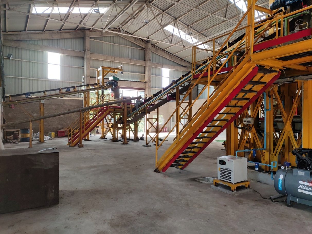 Belt conveyor between yellow platforms in a plant hall